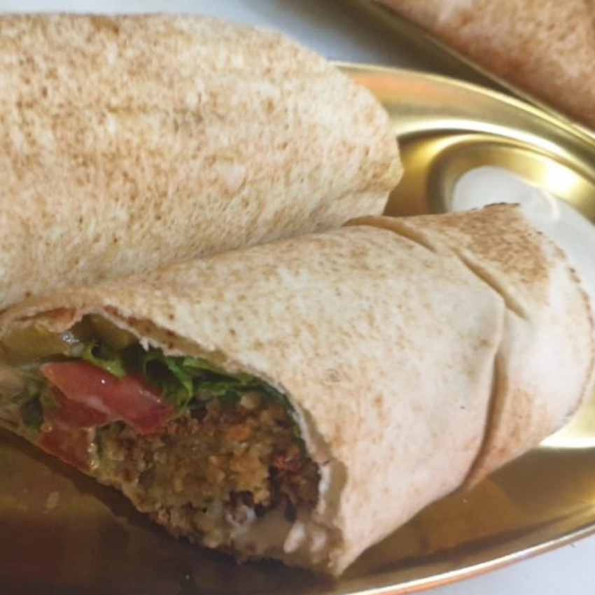 Falafel sandwich with crispy, golden-brown chickpea patties, fresh vegetables, and creamy tahini sauce wrapped in warm pita bread